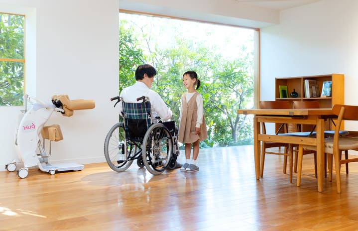 移乗サポートロボットHugと車いすの男性とこどもの写真