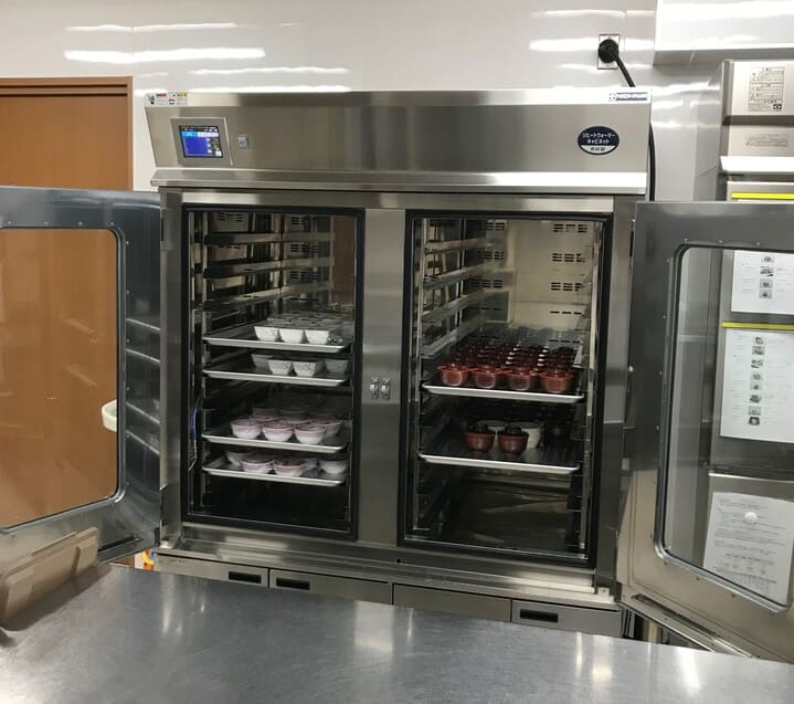 ヒートウォーマーキャビネットに並べられた調理済み真空パック食材